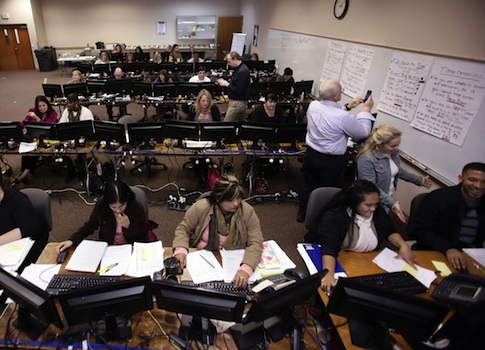 Workers try to process applications for Oregon's health care exchange. The website has not worked since its launch in October