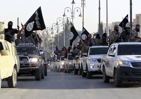 Militant Islamist fighters parade on military vehicles along the streets of northern Raqqa province June 30