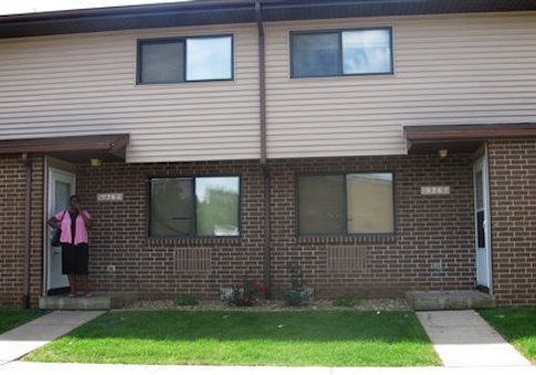 A resident stands in front an apartment where she lives with four children at a public housing apartment complex Thursday, Sept. 4, 2014 in Iowa City, Iowa