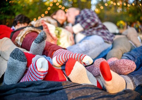 Entwined family socked feet lying on blanket in woods