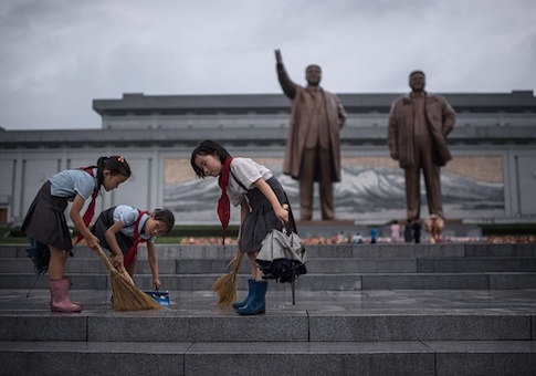 Students clean the steps in front of the statues of late North Korean leaders Kim Il-Sung and Kim Jong-Il at Mansu hill as the country marks 'Victory Day' in Pyongyang on July 27