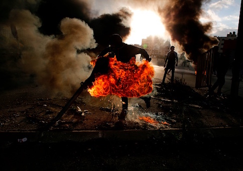 A Palestinian protester runs after catching fire during clashes with Israeli troops at a protest against US President Donald Trump's decision to recognize Jerusalem as the capital of Israel