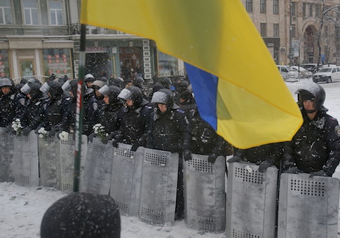 A Ukrainian national flag is waved by pro-European protesters as Ukrainian riot police block the road 