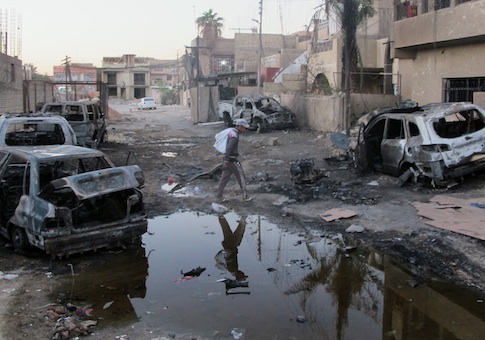 An Iraqi man inspects the aftermath of a bombing in the Baghdad al-Jadidah district
