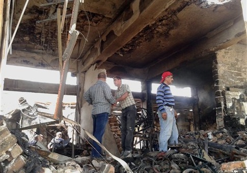 People inspect buildings damaged by an Iraqi government airstrike on the Islamic State in Iraq and the Levant controlled city of Mosul