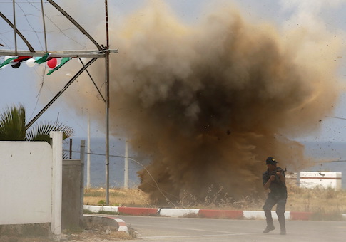Member of Palestinian security forces loyal to Hamas demonstrates his skills as smoke rises following an explosion during a military graduation ceremony in Gaza City