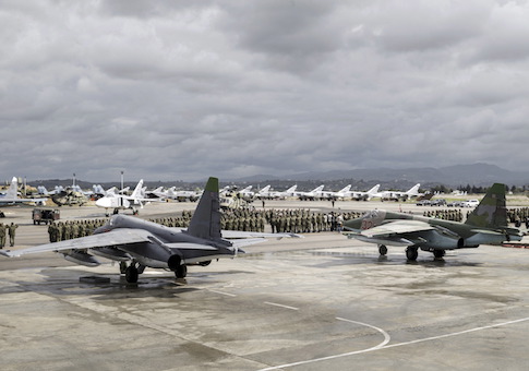 Russian and Syrian servicemen line up near military jets during a ceremony dedicated to the withdrawal of Russian troops from Syria