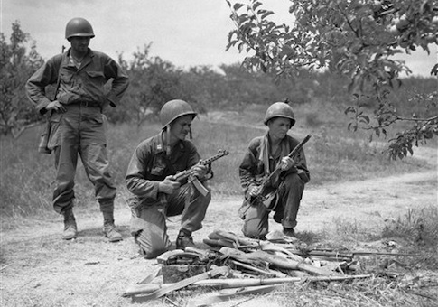 U.S. troops examine North Korean weapons picked up from enemy dead during heavy fighting the preceding night