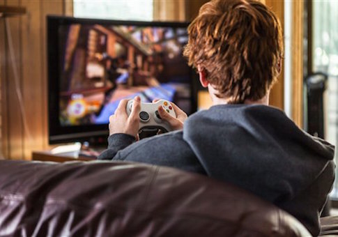 Teenager playing video games at home