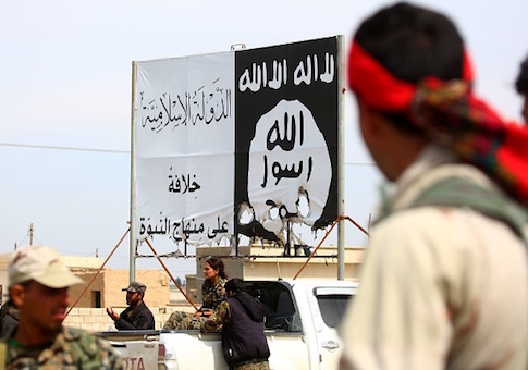 Members of the US-backed Syrian Democratic Forces (SDF), made up of an alliance of Arab and Kurdish fighters, stand under an Islamic State group banner