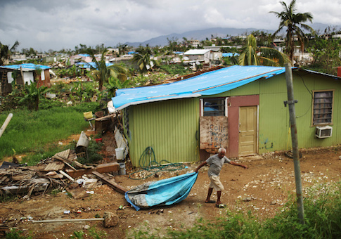 A local resident cleans debris near his damaged home in an area without electricity in San Isidro, Puerto Rico